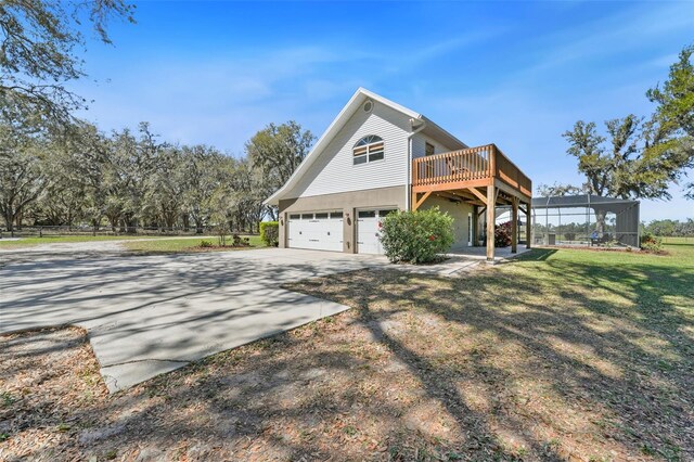 view of property exterior with stucco siding, a lawn, concrete driveway, an attached garage, and a wooden deck