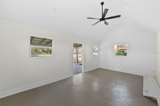 unfurnished room featuring lofted ceiling, a healthy amount of sunlight, baseboards, and concrete floors