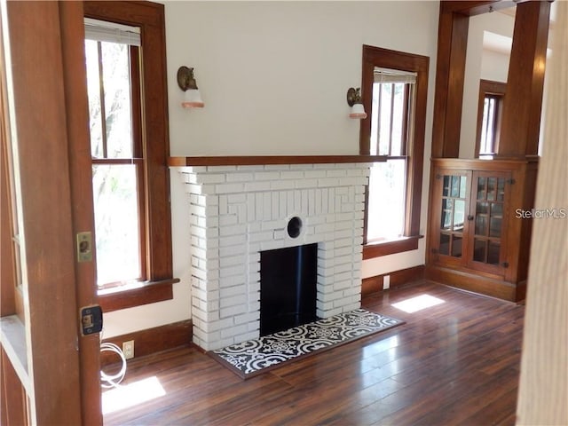 unfurnished living room with baseboards, wood finished floors, and a fireplace