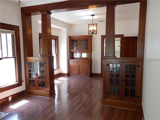 interior space with baseboards, dark wood finished floors, decorative columns, crown molding, and a chandelier