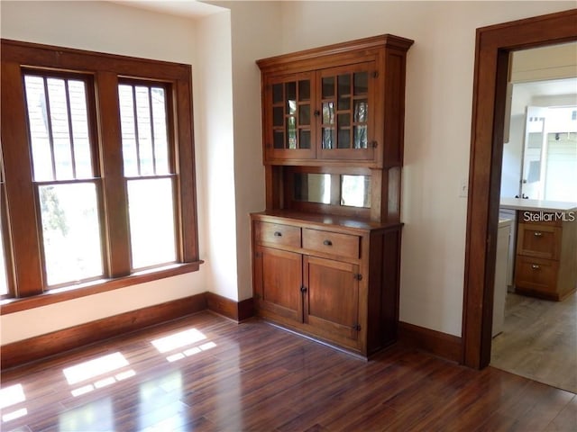 unfurnished dining area featuring baseboards and dark wood-style flooring