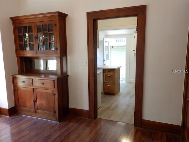 corridor with dark wood-style floors and baseboards