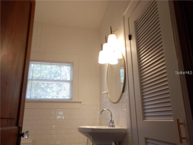 bathroom with a sink and tile walls