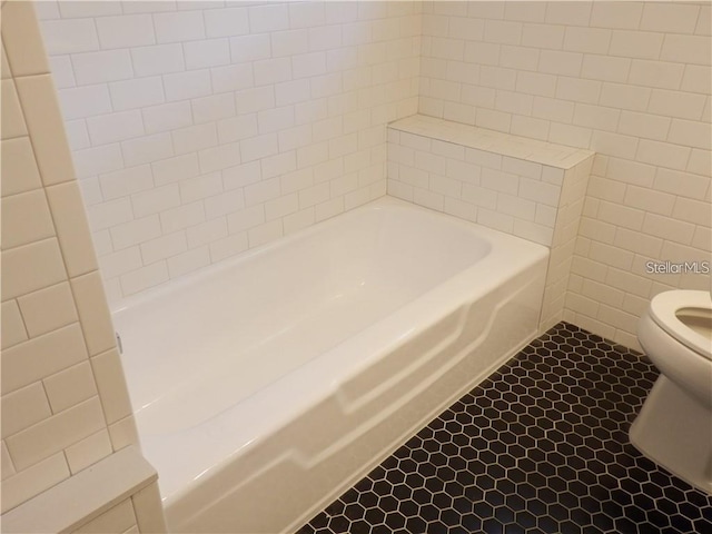 bathroom with tile patterned floors, toilet, a bathtub, and tile walls