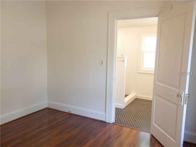 empty room featuring baseboards and dark wood-style flooring