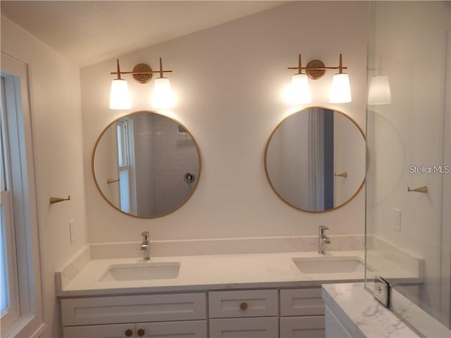 full bathroom featuring lofted ceiling, double vanity, and a sink