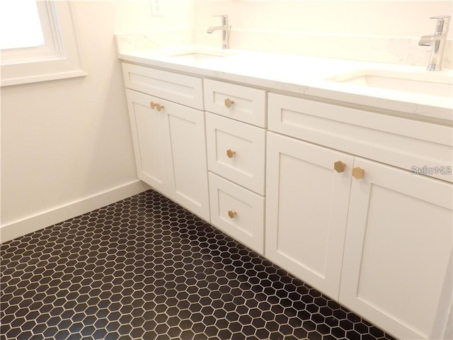 full bath with double vanity, baseboards, and a sink