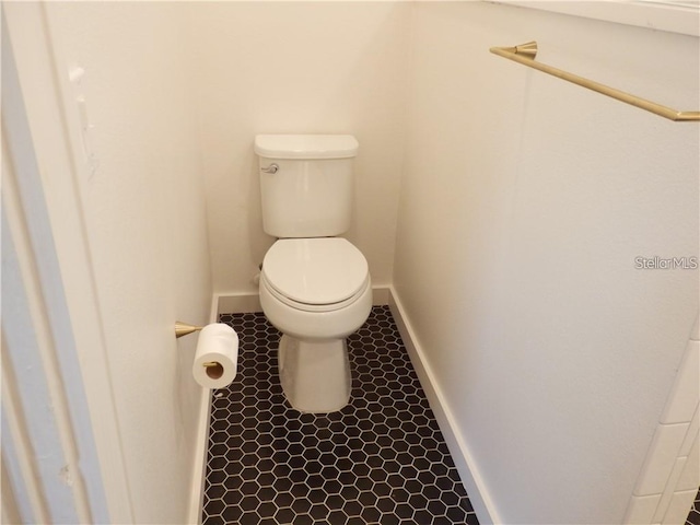 bathroom with baseboards, toilet, and tile patterned flooring