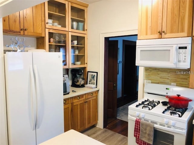 kitchen featuring white appliances, glass insert cabinets, light wood-type flooring, and light countertops