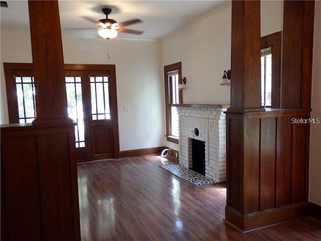 foyer entrance featuring a brick fireplace, baseboards, a ceiling fan, and dark wood-style flooring