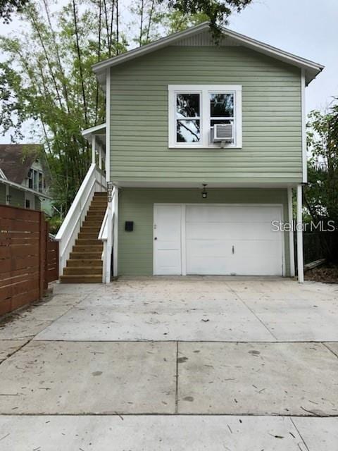 exterior space with a garage, concrete driveway, stairs, and fence