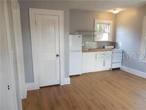 kitchen featuring white appliances, baseboards, and wood finished floors