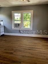 empty room with baseboards and dark wood finished floors