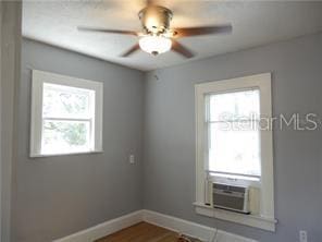 empty room with cooling unit, dark wood-style floors, baseboards, and ceiling fan