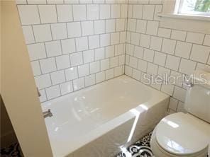 bathroom featuring toilet and tile walls