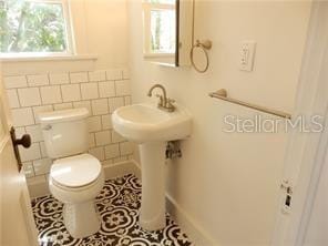 bathroom featuring tile patterned floors, toilet, and tile walls