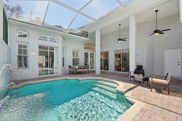 outdoor pool featuring glass enclosure, a patio, and ceiling fan