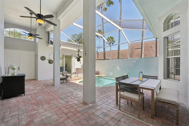 view of patio with glass enclosure, outdoor dining area, a fenced in pool, and a ceiling fan