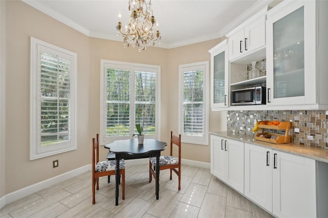 dining area with crown molding, wood finish floors, baseboards, and a chandelier