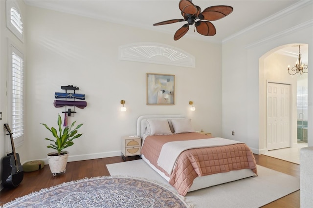 bedroom with crown molding, baseboards, wood finished floors, arched walkways, and a notable chandelier