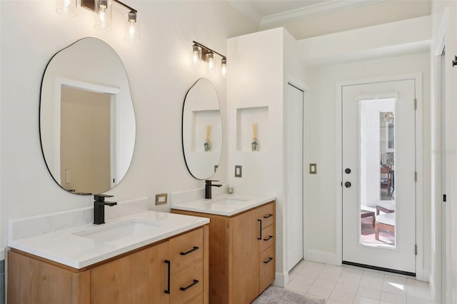 bathroom with tile patterned flooring, ornamental molding, two vanities, and a sink