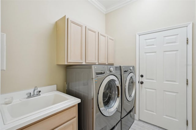 clothes washing area with washer and dryer, ornamental molding, cabinet space, and a sink