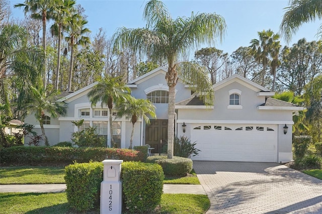 mediterranean / spanish-style house featuring decorative driveway, an attached garage, and stucco siding