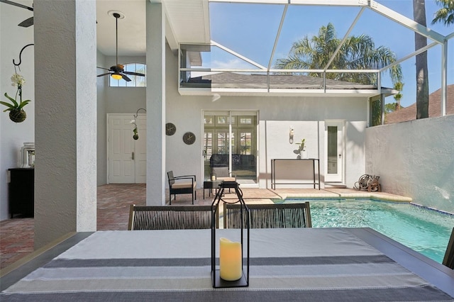 outdoor pool with glass enclosure, a patio area, and a ceiling fan