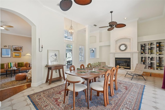 dining room with a high ceiling, ornamental molding, and ceiling fan with notable chandelier