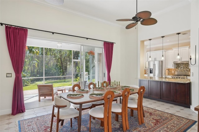 dining space featuring light floors, crown molding, baseboards, and ceiling fan