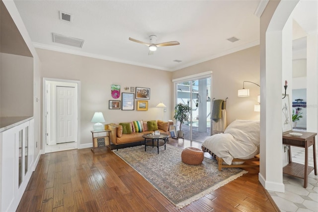 living area featuring baseboards, wood-type flooring, a ceiling fan, and crown molding