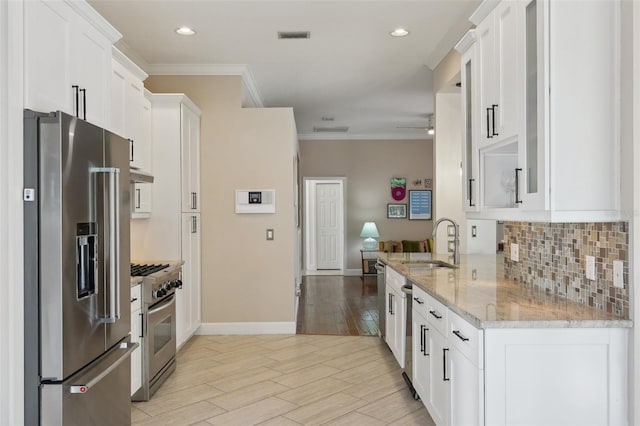 kitchen with a sink, decorative backsplash, stainless steel appliances, white cabinets, and crown molding