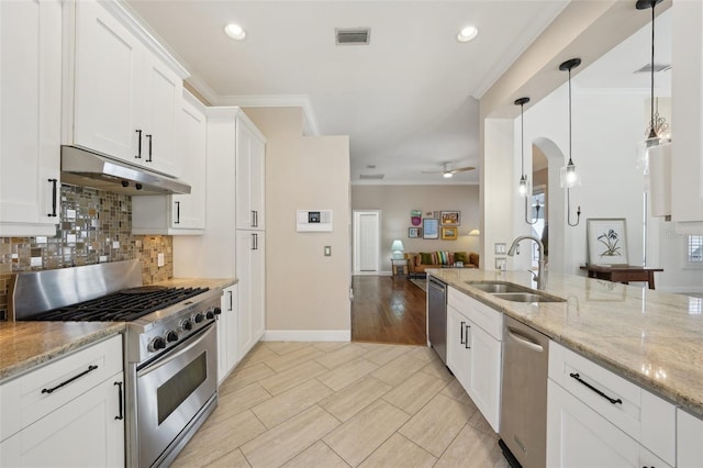 kitchen featuring arched walkways, a sink, stainless steel appliances, under cabinet range hood, and tasteful backsplash