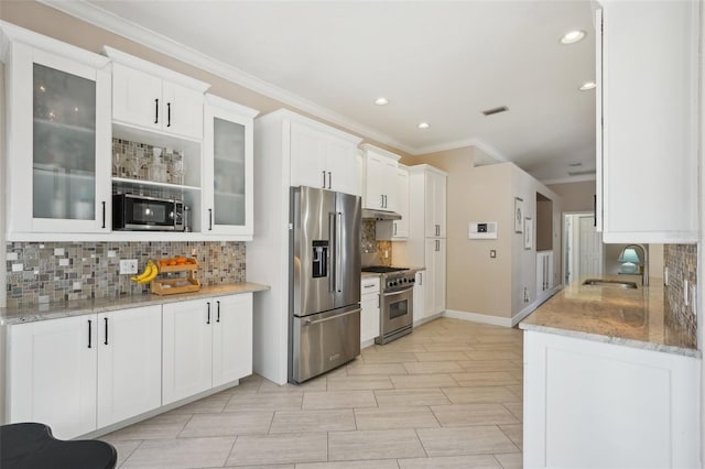 kitchen with under cabinet range hood, premium appliances, decorative backsplash, white cabinets, and a sink