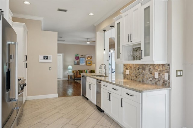 kitchen featuring decorative backsplash, ornamental molding, stainless steel appliances, and a sink