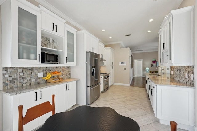 kitchen featuring glass insert cabinets, crown molding, high quality appliances, white cabinets, and a sink