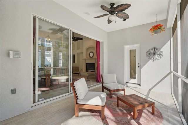 sunroom / solarium featuring ceiling fan and a fireplace