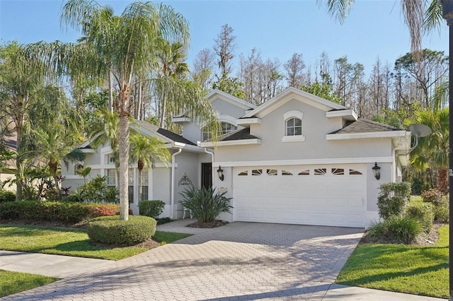 view of front of house featuring stucco siding, decorative driveway, and a garage