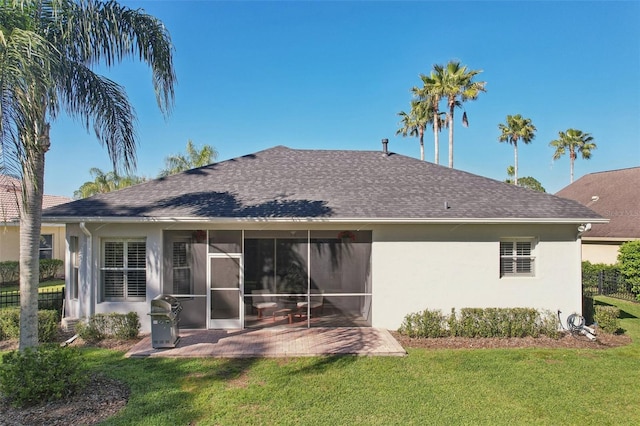 back of property with roof with shingles, a yard, a sunroom, and stucco siding