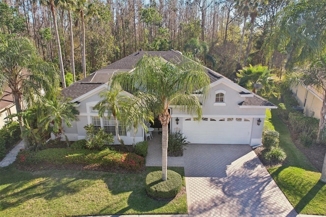 view of front of home with stucco siding, decorative driveway, a garage, and a front yard