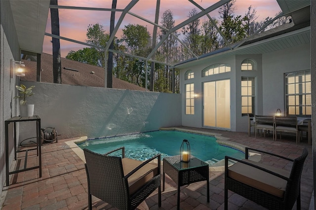 pool at dusk with glass enclosure, a patio, a fenced in pool, and fence