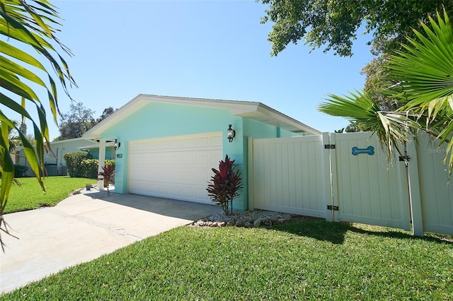 view of front of home with driveway, a gate, fence, a front yard, and an attached garage