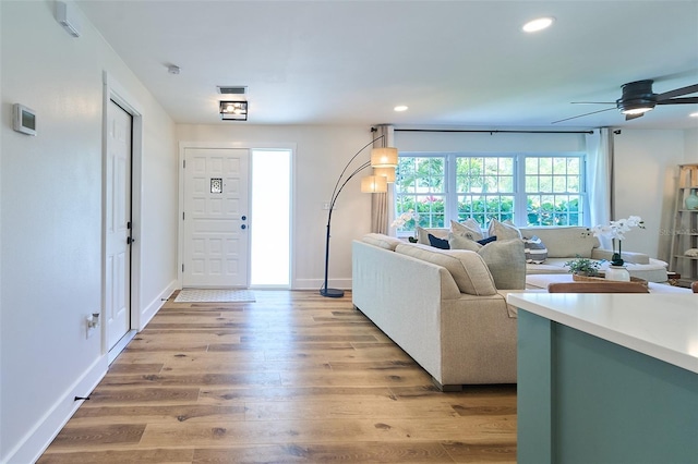 living room with visible vents, baseboards, recessed lighting, light wood-style flooring, and a ceiling fan