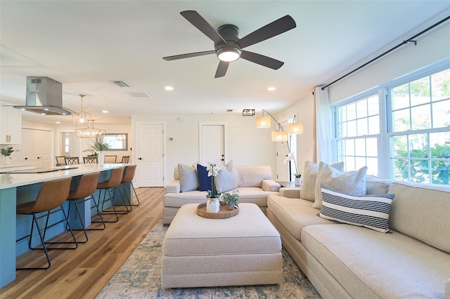 living room with ceiling fan with notable chandelier, light wood-style flooring, recessed lighting, and visible vents