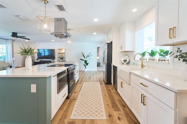 kitchen with visible vents, a sink, island exhaust hood, stainless steel appliances, and a kitchen island with sink