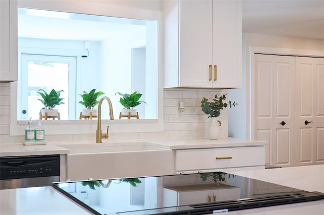 kitchen featuring dishwasher, light countertops, decorative backsplash, white cabinetry, and a sink