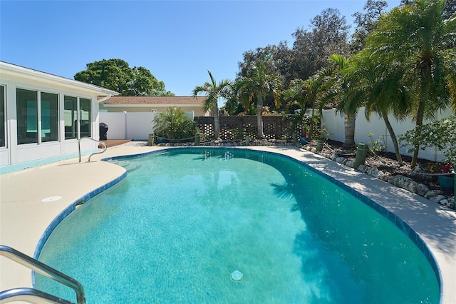 view of swimming pool with a patio area, a fenced backyard, a fenced in pool, and a sunroom