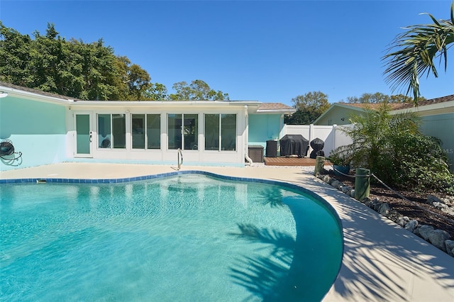 view of pool with a patio area, a fenced in pool, a sunroom, and fence