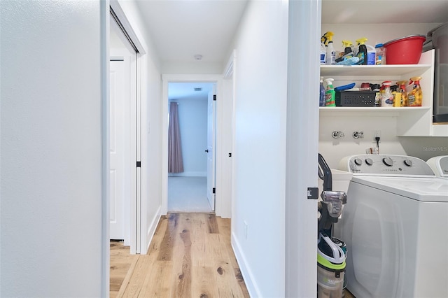 clothes washing area with laundry area, light wood-style floors, independent washer and dryer, and baseboards