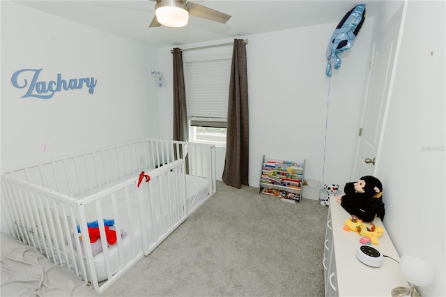 bedroom featuring a crib, carpet floors, and ceiling fan